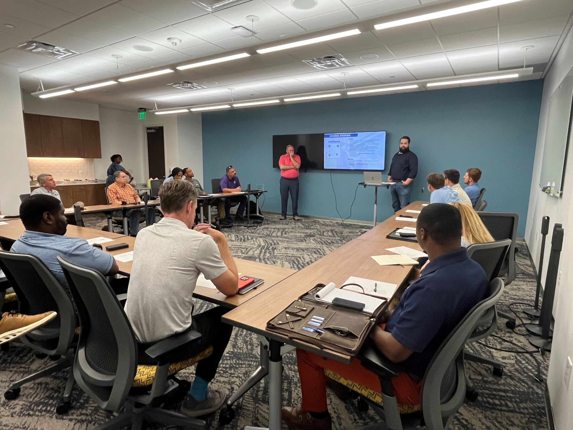 Construction trade partners attending a lunch meeting and presentation in a conference room.