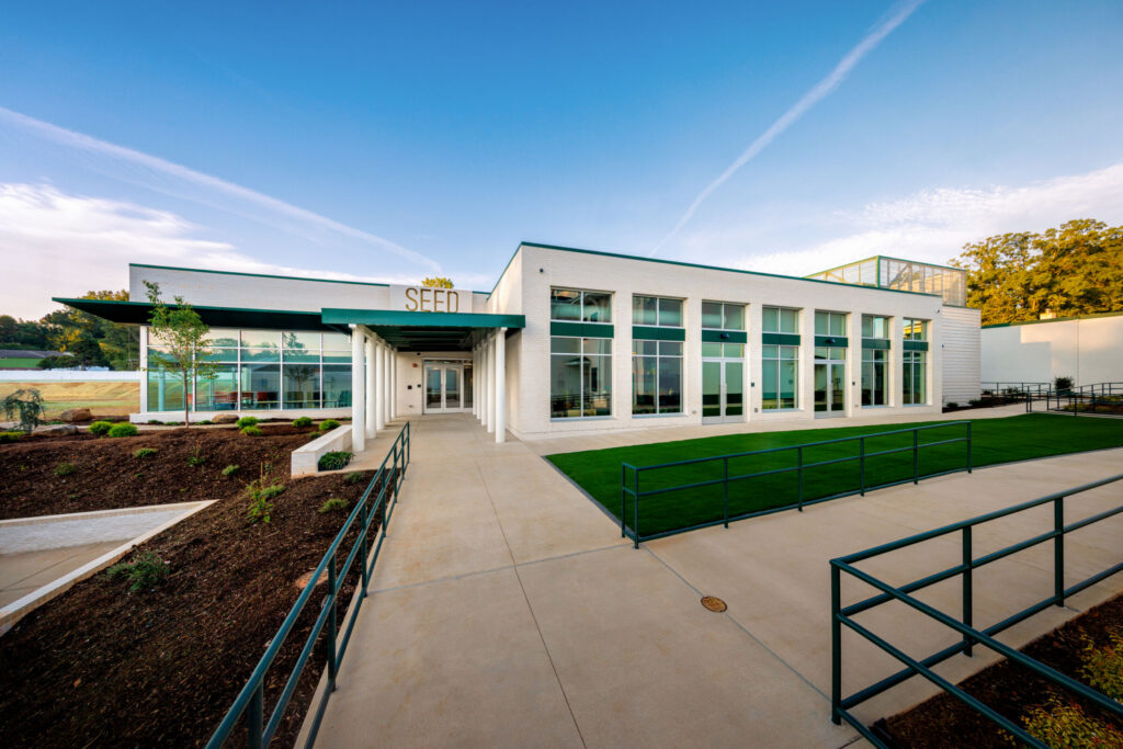 Exterior of the Summit SEED Center featuring a modern white facade, large windows, covered entrance, and landscaped walkways.